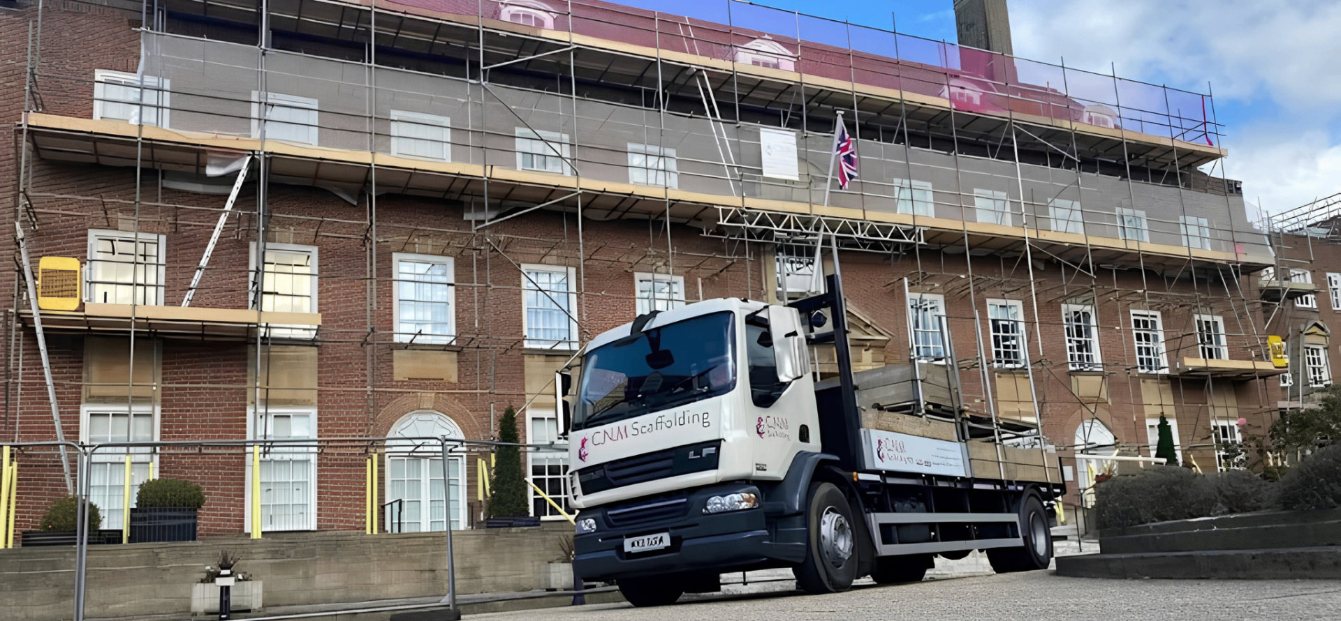 C.N.M Scaffolding branded lorry parked outside a heritage West Sussex building wrapped in independent scaffolding