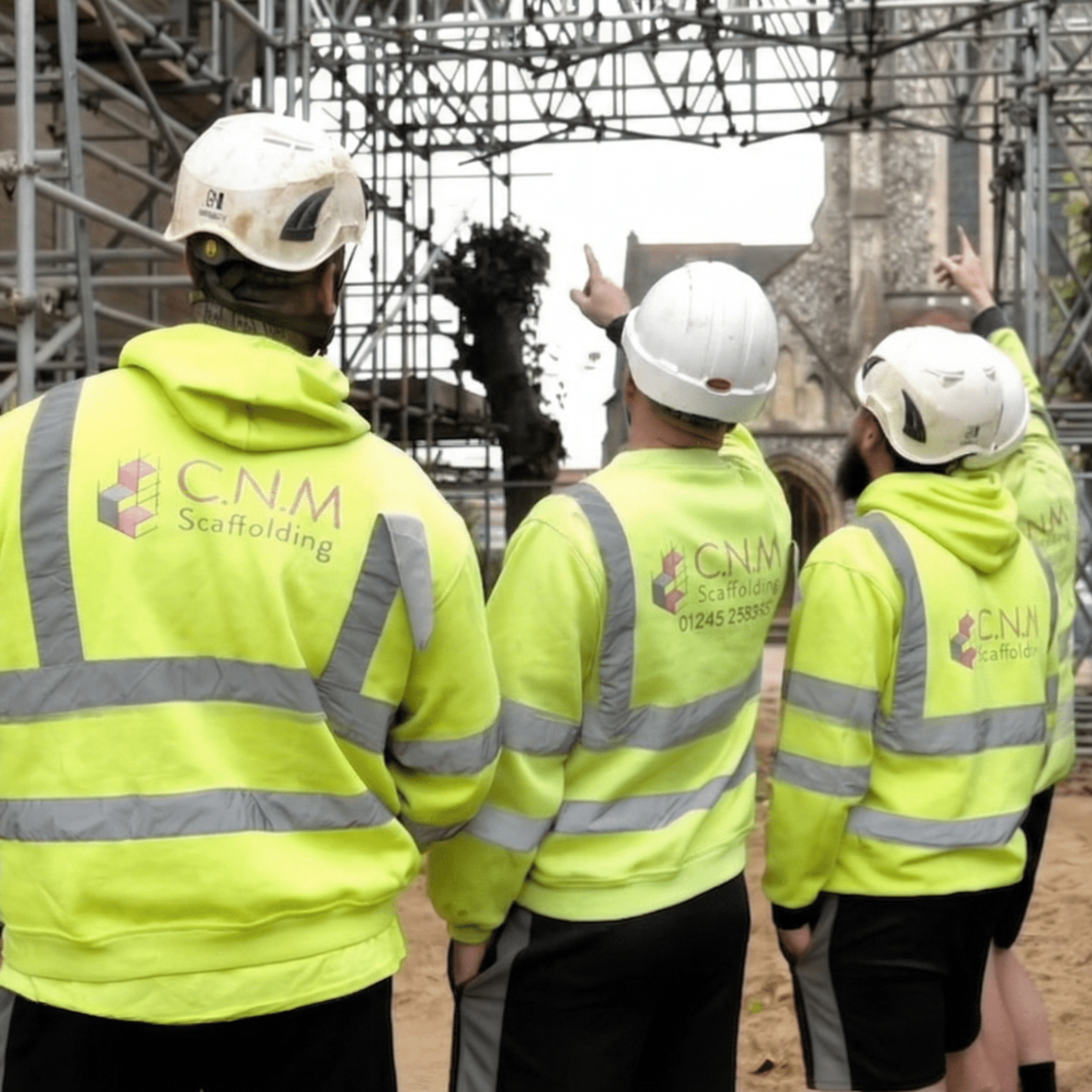 C.N.M Scaffolding team in hi-vis jackets and hard hats on a commercial scaffolding site in West Sussex